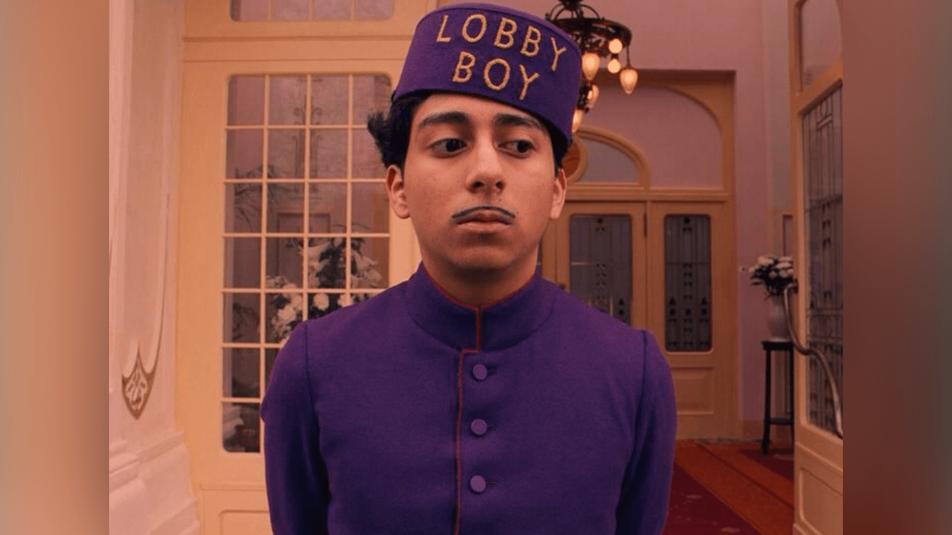 Wes Anderson scene lobby boy with purple outfit